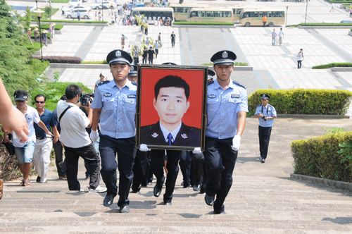 两位民警抬着张磊的遗像缓缓走向烈士碑